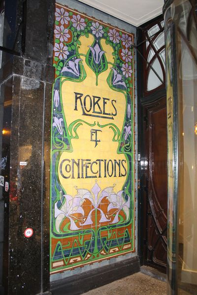 Een geel en groene tegelwand waarop staat 'Robes & Collections'.