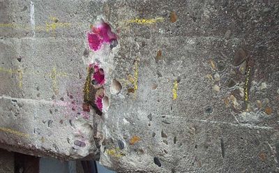 Een scheur in een betonnen muur met roze stippen verf eroverheen