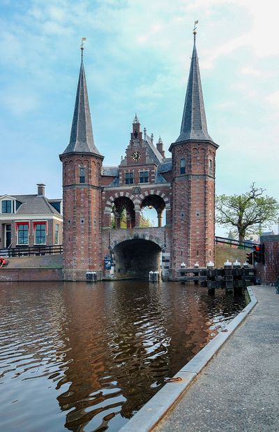 Sneker Waterpoort over het Hoogendsterpijp. De poort heeft aan weerszijden een toren staan. De brug is overdekt met een afdak met een klok erin.