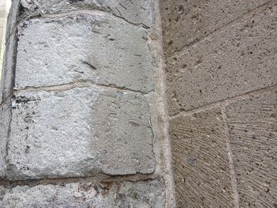Een hoek in een muur met links lichtgrijze stenen en rechts donkergrijze stenen.
