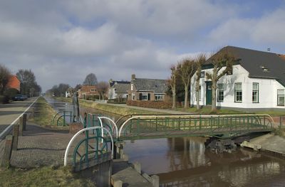 Foto van het dorp Kiel-Windeweer. Te zien zijn huizen met een sloot ervoor waaroverheen een bruggetje ligt.