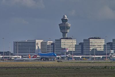 Foto van Schiphol. De luchtverkeerstoren staat achter de gebouwen.