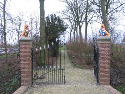Begraafplaats van de familie Buma. De ingang bestaat uit twee bakstenen pilaren met daartussen een smeedijzeren hekwerk. Op de pilaren zijn gekleurde leeuwen met een familiewapen opgenomen. Achter hek een pad dat de begraafplaats opvoert.