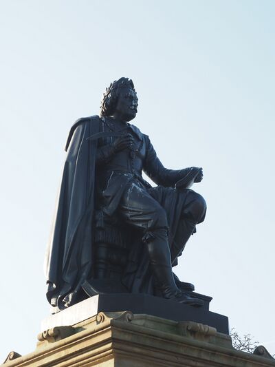 Een zwart standbeeld van een man met daarop vogelpoep.