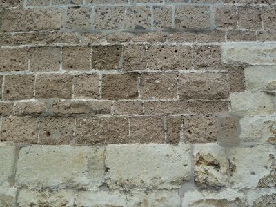 Een muur met bovenin bruine stenen en onderin witte stenen.