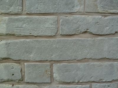 Lichtgrijze blokken steen in een muur gemetseld.