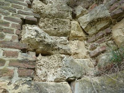 Blokken steen in een muur met veel gaatjes erin.