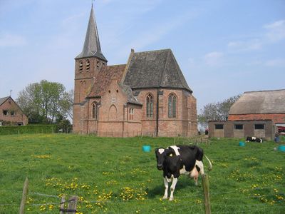 Kerkje in Persingen. In de voorgrond een koe in het weiland.