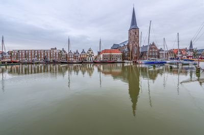 Stadsaanzicht van Harlingen. Te zien is de Zuiderhaven met in de achtergrond een kerk en huizenrijen. Op de voorgrond liggen zeilboten in het water.