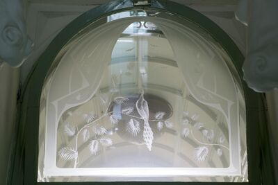 Glas met afbeelding van een pauw op een tak erin geëtst en gestraald.