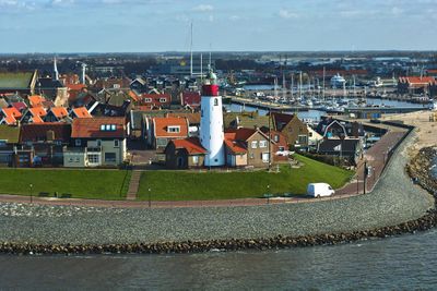 Foto van Urk genomen vanuit de lucht. Vooraan is een vuurtoren te zien en links een kerkje. Rechts achterin is de haven te zien. Verder staan er huizen.