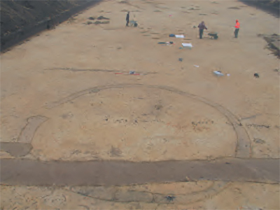 Foto van Archeologen die bezig zijn met een opgraving in Eersel, in het plangebied Kerkebogten. De foto toont een kringgreppel van een grafheuvel uit de Midden-Bronstijd (1800-1500 voor Chr.)