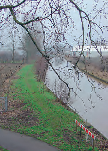 Groen strook gras langs de IJssel. Onderaan loopt een weg die afbuigt naar links.