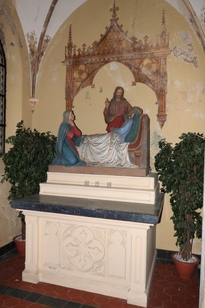 Kleurrijk altaar met daarop een beeldengroep van het sterfbed van Jozef met aan zijn zijde Christus en Maria. Op de wand is een baldakijn geschilderd.