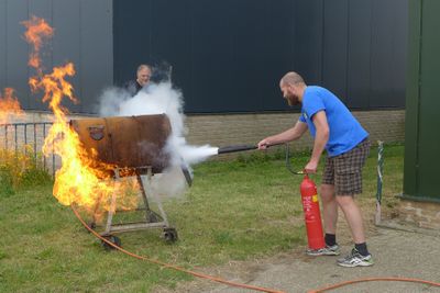 Een man blust een in de brandgevolgen barbecue met een brandblusser.