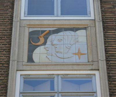 Met tegels is tegen een muur een kunstwerk gemaakt waarop twee gezichten, een ster en een sikkel te zien zijn.