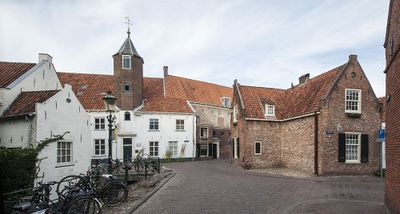 Foto van een samenkomden straatjes in Amersfoort. Een van de huizen heeft een torentje. De linker huizen zijn wit geverfd, de rechter zijn baksteenkleurig.
