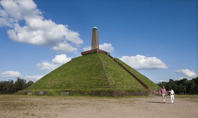 Piramide van Austerlitz. Groene piramidevormige zandheuvel met bovenop een stenen obelisk.