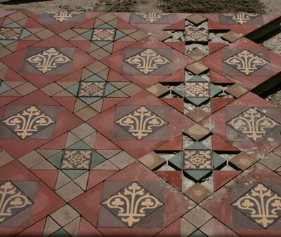 Renovatieproces van een serrevloer met tegels die in hun originele patroon worden teruggelegd.