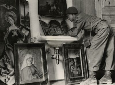 Zwartwit foto van een soldaat die leunt op een wasbak, met daar omheen oude schilderijen in hun lijst