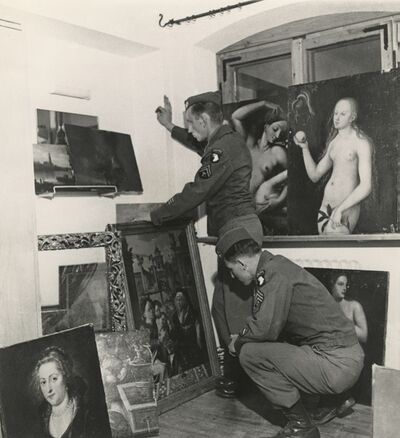 Zwart-witfoto van twee militairen met een aantal schilderijen