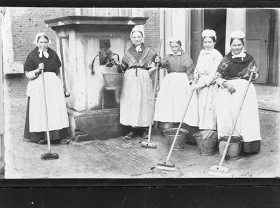 Historische foto van werksters bij een oude pomp op een binnenplaats