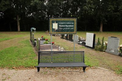 Op de voorgrond een informatiebord met daarachter een grafveld waar een aantal grafmonumenten in het gras liggen.