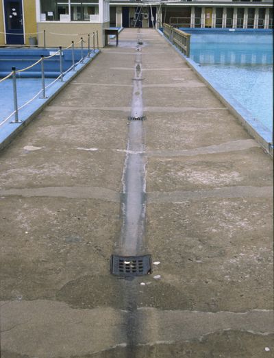 Een betonnen vloer tussen twee zwembaden