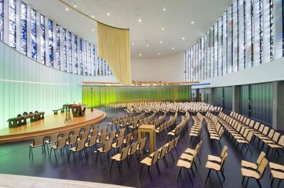 modern kerkinterieur met stoelen, glas-in-loodvensters, tussenwanden, altaar en gordijn