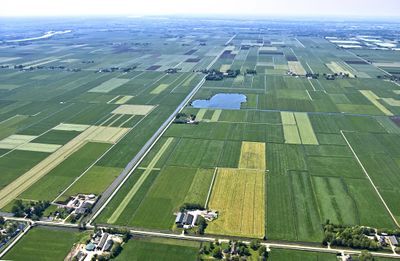 Luchtfoto van Mastenbroek. Veel weiland met in het midden een meertje.