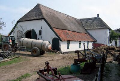 Foto van karakteristiek boerenerf in gebruik, in Persingen (Gelderland), met een schuur en daarvoor een mestwagen
