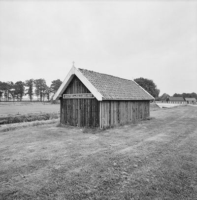 Zwart-wit foto van een huisje middenin een weiland. Erop geschreven staat: Dijkstoel van Salland 5e rot.
