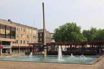 De fontein, gevuld met water, met een aantal spuitmonden die water spuiten. In het midden staat het beeld van Tajiri. Daarachter de overkappingen.