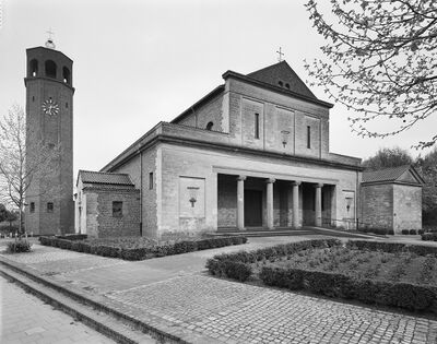 kerkgebouw met klokkentoren, zuilen en voorplein met beplanting