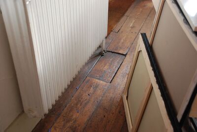 Een plank ligt iets lager dan de rest van de planken in de houten vloer.