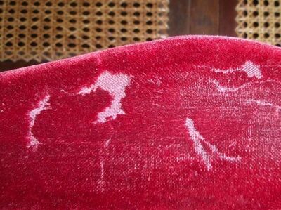 Foto van rood fluwelen stoelbekleding met schade