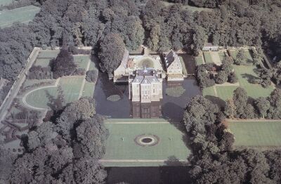 Luchtfoto van het kasteel omringd door de gracht en formele tuinen. Hier omheen staan bossen.
